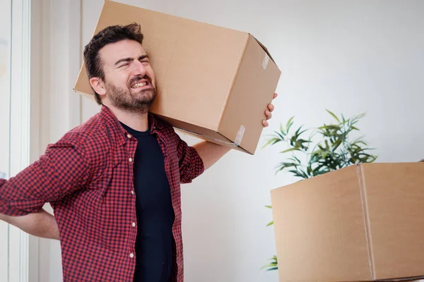 Man moving boxes and feeling back pain because heavy weight — Stock Photo, Image
