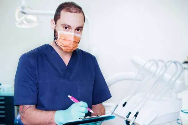 Smiling male dentist writing medical prescription chart