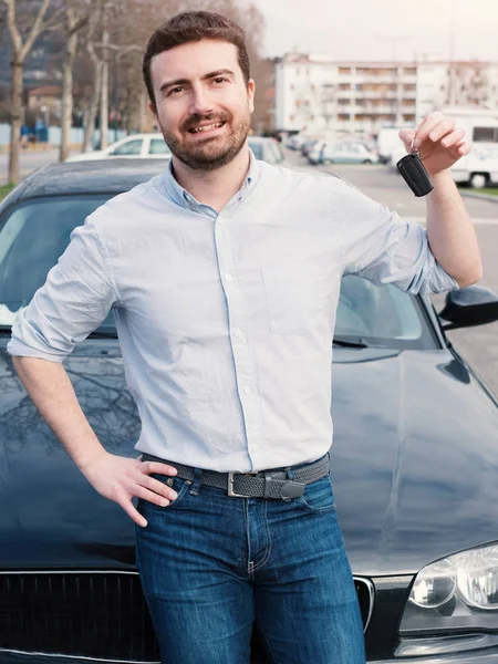 Man holding a car key next to his vehicle — Stock Photo, Image