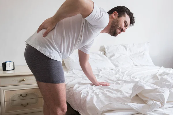 El hombre despierta por la mañana y sufre dolor de espalda —  Fotos de Stock