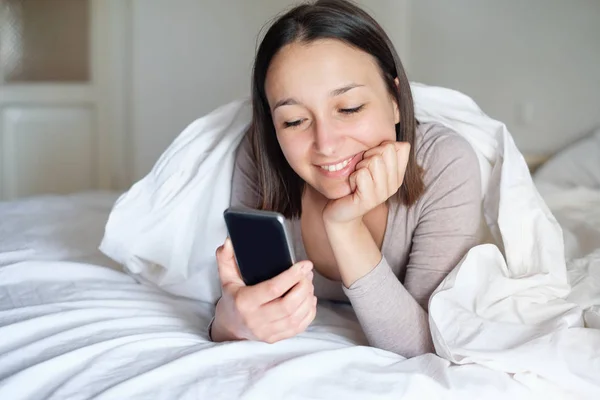 Fiatal nő, és mozgatható telefon az ágyban — Stock Fotó