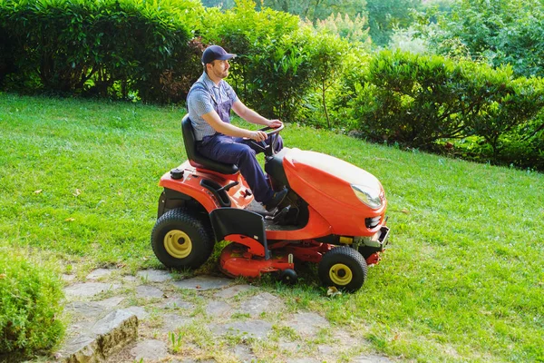 Tuinman rijden een paardrijden grasmaaier in tuin — Stockfoto