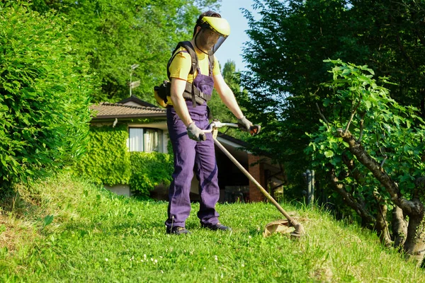 Jardinero profesional utilizando una recortadora de bordes en el jardín en casa —  Fotos de Stock