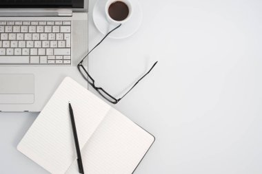 Beyaz renk arka plan üzerinde kahve Kupası, defter ve kopya alanı ile modern çalışma alanı. Üstten Görünüm.