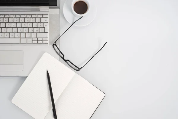 Moderna arbetsytan med kaffe cup, anteckningsbok och kopia utrymme på vit färg bakgrunden. Ovanifrån. — Stockfoto