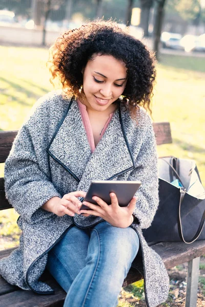 Mulher negra usando o aplicativo no banco sentado tablet — Fotografia de Stock