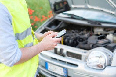 Bir adam onun araba bozulduğunda yardımını içinde telefon kullanıyor