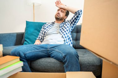 Taşındıktan sonra etrafı büyük kutularla çevrili genç yorgun adam.