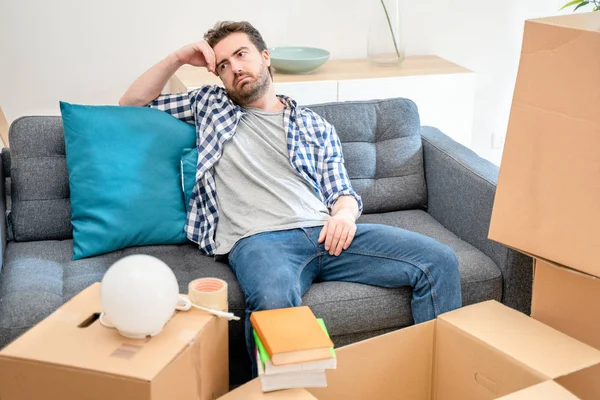 Man sitting on sofa with belongings in living room ready to move