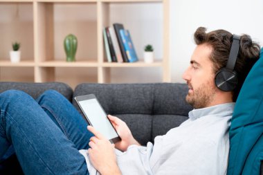 Genç adam film izliyor ve dijital tablet kullanıyor.