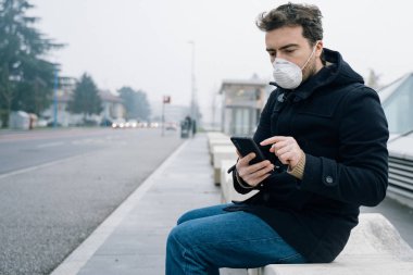 Şehirde hava kirliliğine karşı maske takmış bir adam yürüyor