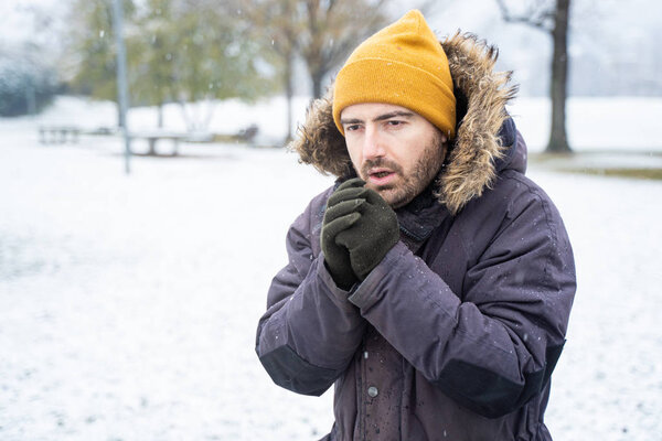 Man wearing warm clothes freezing in the snow