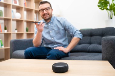 Ev asistanı bluetooth hoparlörü kullanan adam