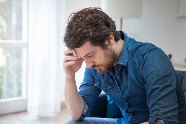 Tankeväckande pensiv allvarlig hane sitter på soffan hemma — Stockfoto