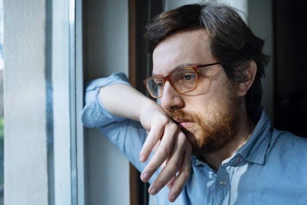 Portrait of one guy longing and looking through window — Stock Photo, Image