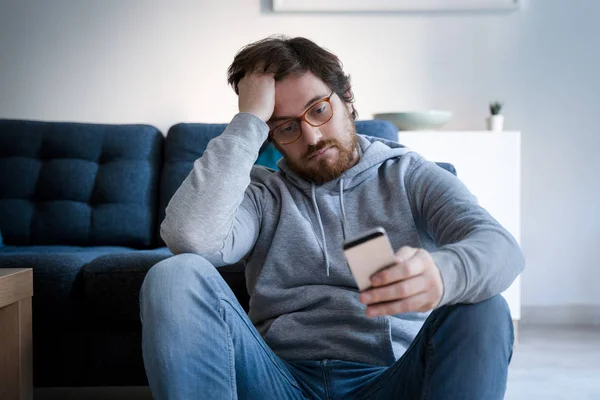 Retrato del tipo preocupado sosteniendo el teléfono celular en casa —  Fotos de Stock