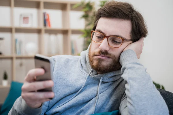 Yalnız adam koltukta cep telefonunu kontrol ediyor.