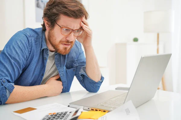 Bezorgde man zit in het kantoor thuis en met behulp van een creditcard — Stockfoto