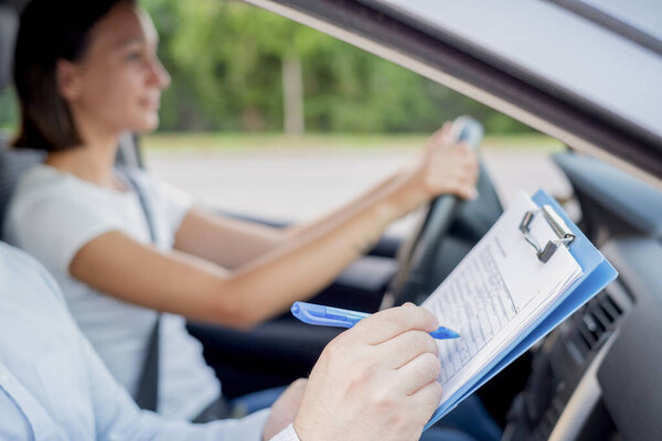 Instructor of driving school giving exam while sitting in car