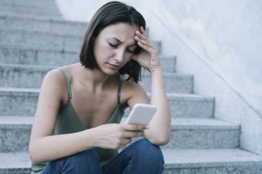 Üzgün kadın şehirde akıllı telefon online içerik kontrol