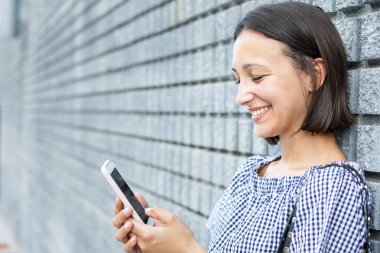 Şehirde cep telefonuyla mesajlaşan genç bir kız.