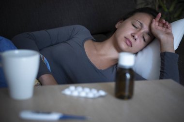 Evdeki kanepede yatan kadın baş ağrısı çekiyor.