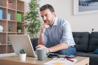 Evde çalışan bir adam internet bağlantısı kullanıyor.