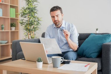 Evde çalışan bir adam internet bağlantısı kullanıyor.