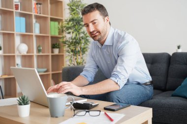 Evde çalışan bir adam internet bağlantısı kullanıyor.