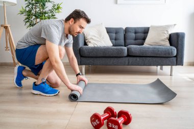 Genç beyaz adam evde fiziksel egzersize hazır.