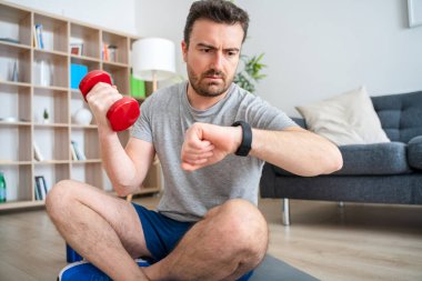 Genç, aktif bir adam, eğitimler sırasında akıllı saatleri kontrol ediyor.