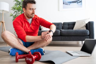 Genç, aktif bir adam, eğitimler sırasında akıllı saatleri kontrol ediyor.