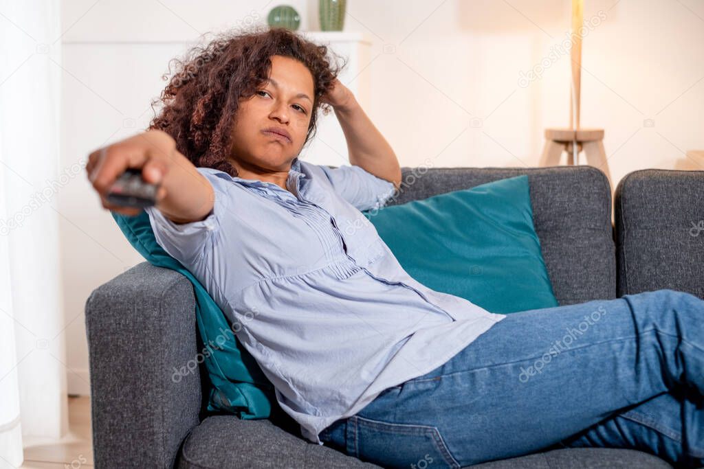 Black tired woman relaxing at home watching tv
