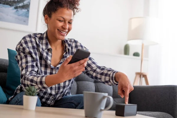 Happy black woman using smart speaker at home