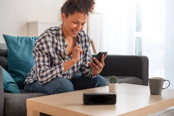 Happy black woman using smart speaker at home