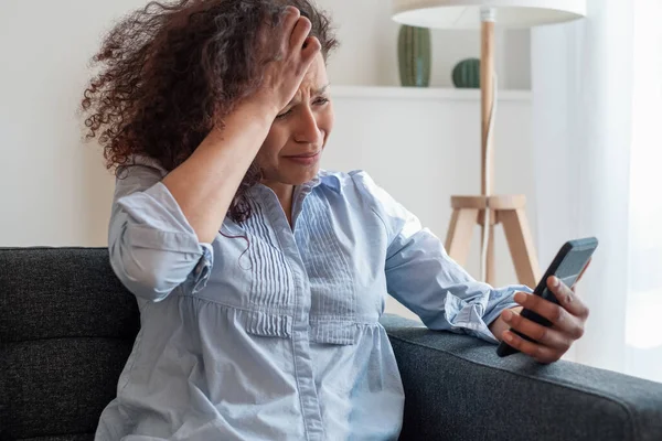 Sad black woman reading bad news on mobile phone