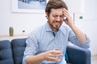 Evde baş ağrısı hisseden ciddi bir erkek portresi.