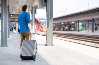 Tekerlekli sandalyedeki adam tren istasyonunda trene biniyor.