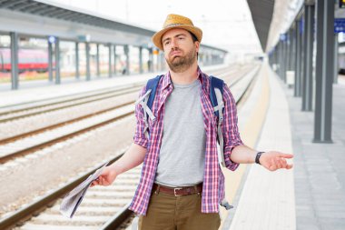 Tren bekleyen üzgün ve kızgın bir turist.