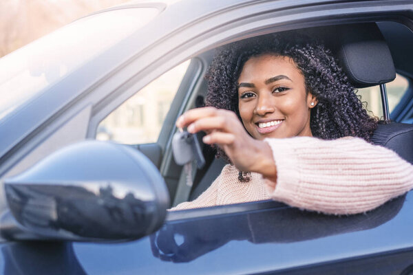 Happy black woman driving her new car holding key