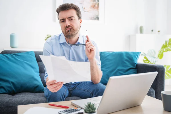 Troubled guy calculating bills tax expenses and counting home business