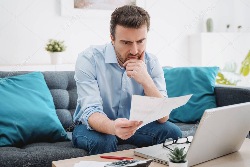 Troubled guy calculating bills tax expenses and counting home business