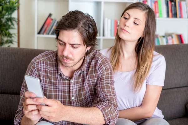 Jealous angry woman spying boyfriend and watching his mobile phone