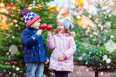 İki küçük çocuk Noel piyasasında yeme şeker elma