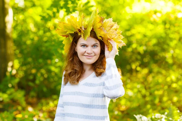 Joyeux jeune femme avec guirlande de feuilles d'érable d'automne dans le parc . — Photo