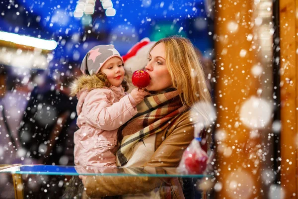 Mujer y niña comiendo manzana cristalizada en la marca de Navidad —  Fotos de Stock