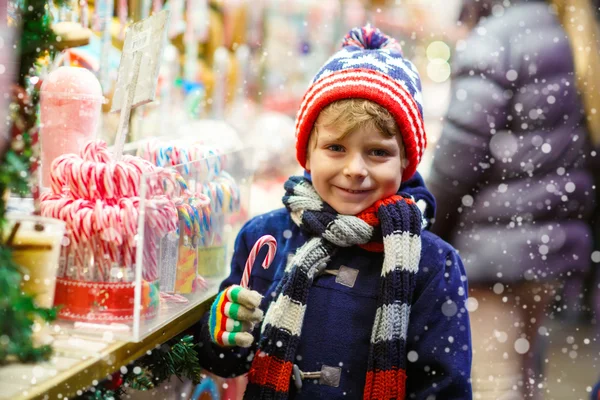 Malé dítě chlapec s cukrové třtiny stojí na vánoční trh — Stock fotografie