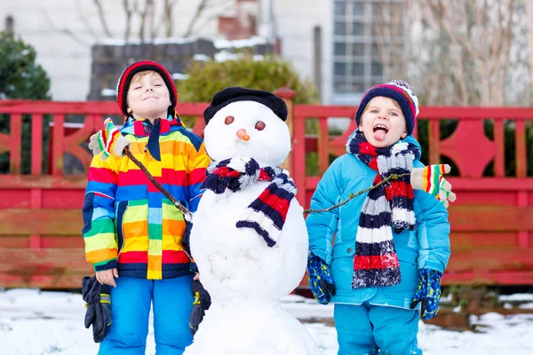 Twee broers en zussen jongetjes een sneeuwpop maken — Stockfoto
