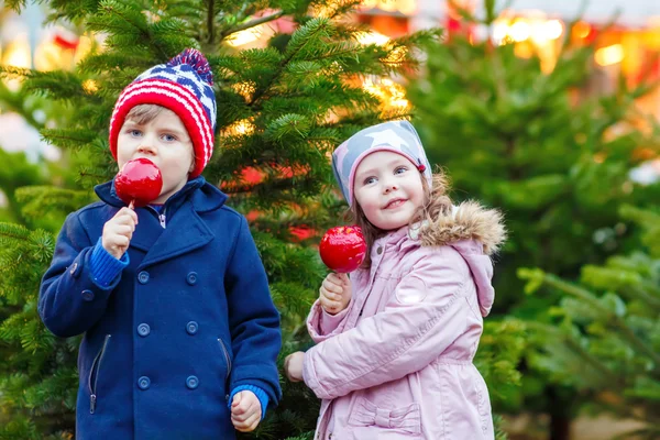 Двое маленьких детей едят сахарное яблоко на Рождественской ярмарке — стоковое фото