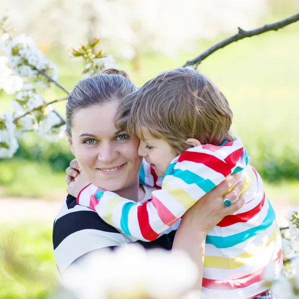 Jovem mãe e menino se divertindo no jardim florido — Fotografia de Stock